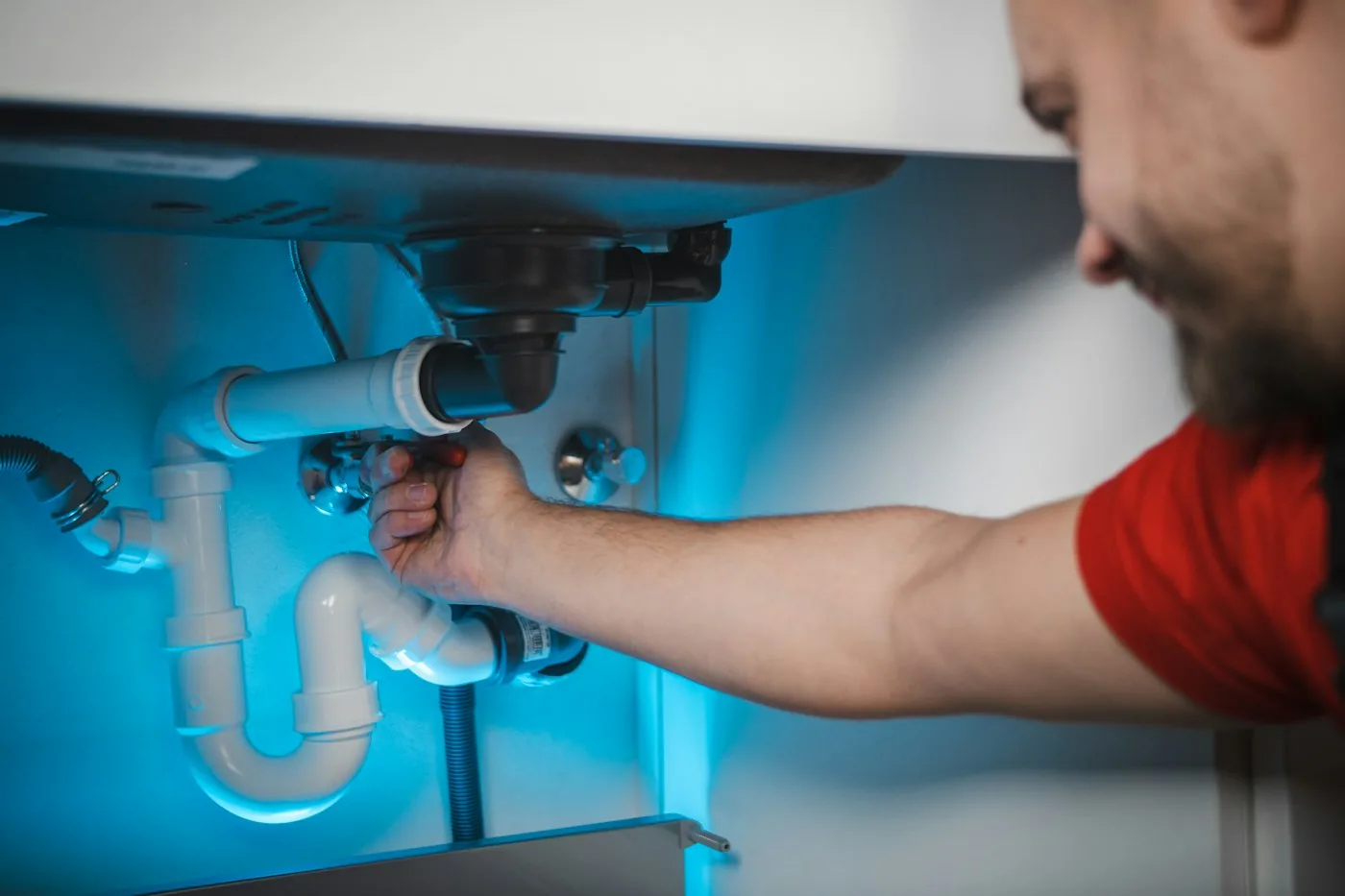 Monteur repariert den Siphon unter einem Waschbecken